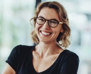 Portrait,Of,Smiling,Businesswoman,Standing,In,Office,With,Colleagues,Meeting